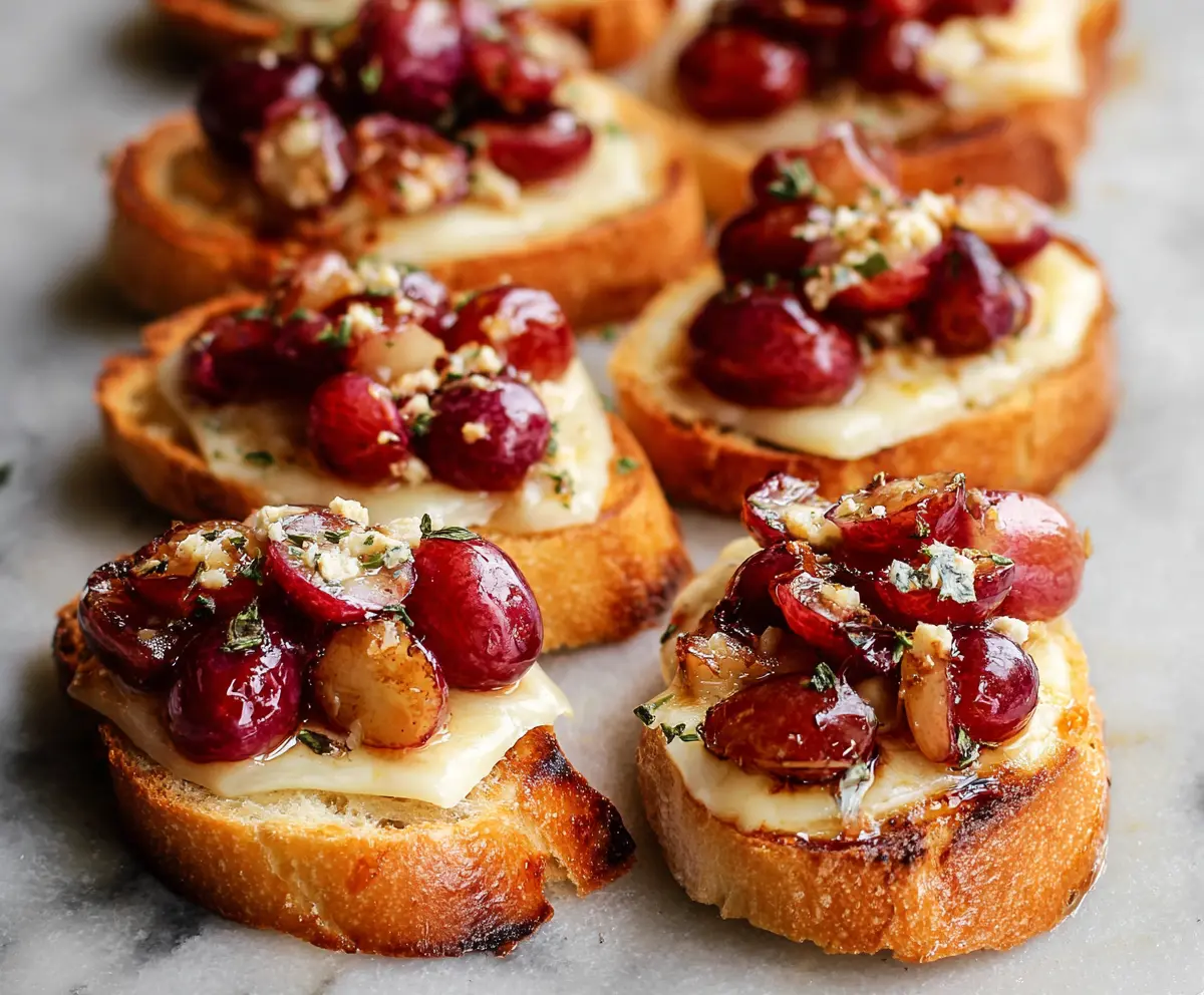 Delicious roasted grape and melted Brie cheese crostini served on a wooden platter.