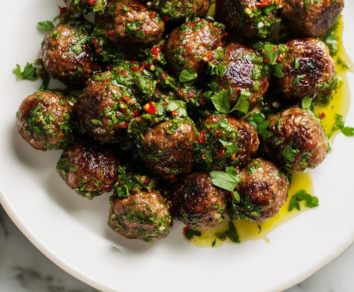 Delicious Chimichurri Meatballs served on a plate with fresh herbs and vibrant sauce.