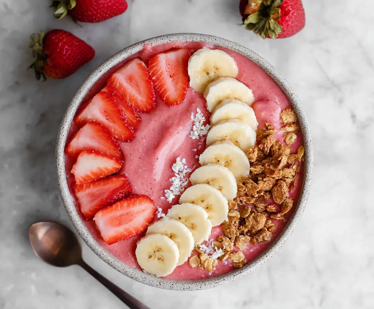 Vibrant strawberry banana smoothie bowl topped with fresh fruit and granola for a healthy breakfast