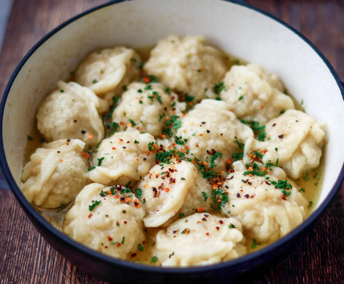 Delicious sourdough discard dumplings served on a rustic plate with fresh herbs.