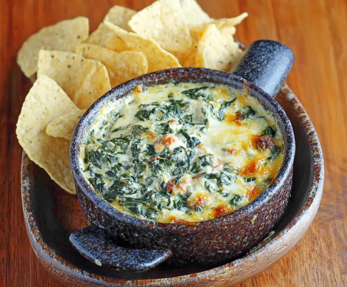 Delicious Cheddars Santa Fe Spinach Dip served with crispy chips on a festive table.