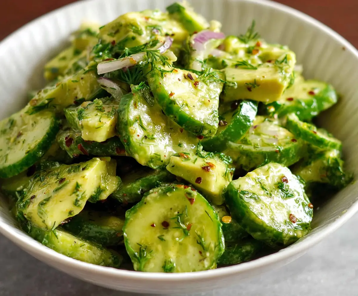 Fresh cucumber and creamy avocado salad garnished with herbs, perfect for a healthy meal.