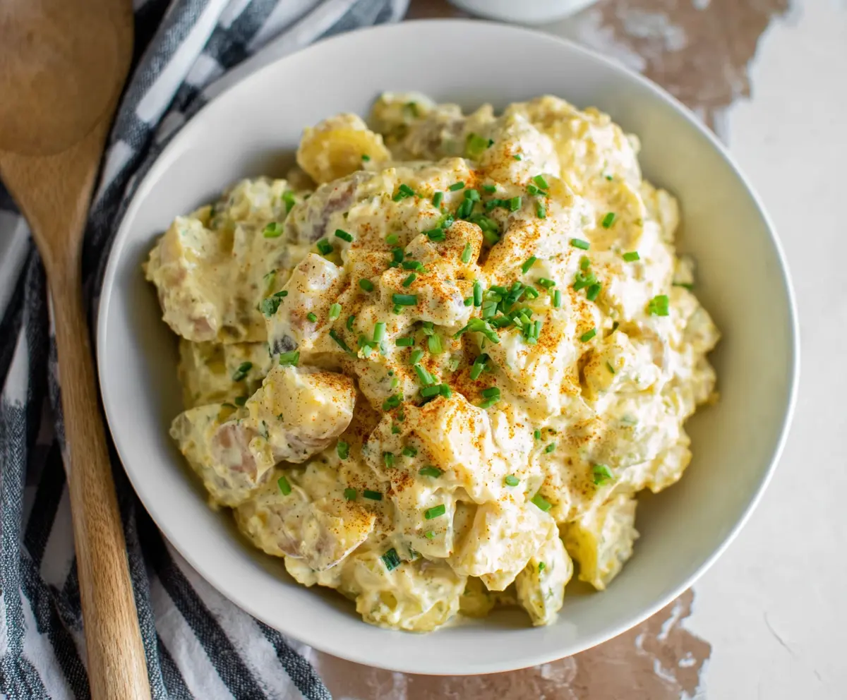 Creamy potato salad with chopped herbs and mayonnaise, served as a refreshing side dish.