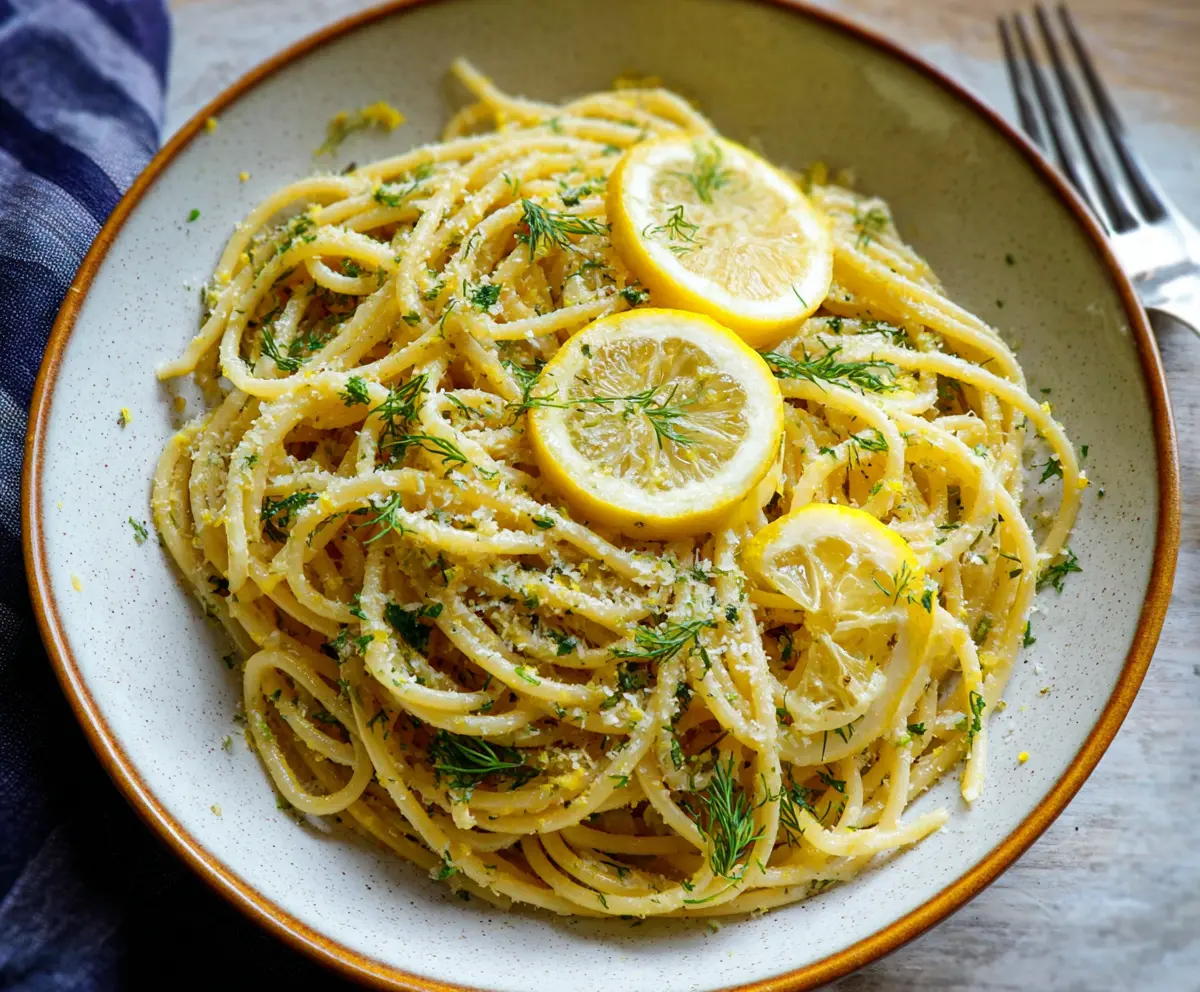 Delicious browned butter lemon dill pasta served in a white bowl with fresh herbs.